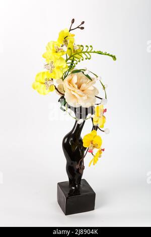 Composizione con fiori artificiali in vaso su sfondo bianco. Ekibana dalle orchidee artificiali gialle e rosa. Foto Stock