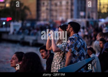 Istanbul, Turchia. 13th maggio 2022. La gente scatta foto alla spiaggia di Kadikoy. Mentre il sole tramonta nelle ore serali di Istanbul, c'è stata una festa visiva nel cielo dal molo di Kadikoy. Alcuni cittadini hanno preso il bellissimo paesaggio con il tramonto con i loro telefoni cellulari. Credit: SOPA Images Limited/Alamy Live News Foto Stock