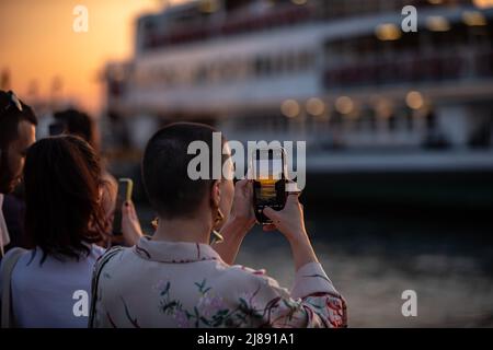 Istanbul, Turchia. 13th maggio 2022. La gente scatta foto alla spiaggia di Kadikoy. Mentre il sole tramonta nelle ore serali di Istanbul, c'è stata una festa visiva nel cielo dal molo di Kadikoy. Alcuni cittadini hanno preso il bellissimo paesaggio con il tramonto con i loro telefoni cellulari. Credit: SOPA Images Limited/Alamy Live News Foto Stock