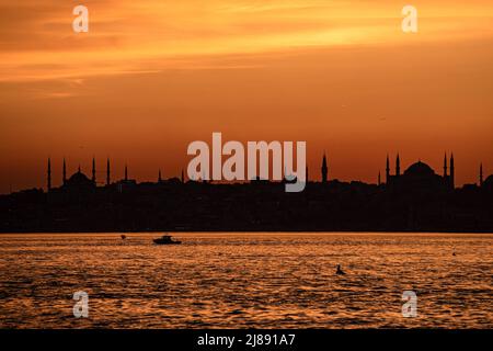 Istanbul, Turchia. 13th maggio 2022. La silhouette della moschea di Hagia Sophia e della Moschea Blu ha creato una splendida vista sui tramonti. Mentre il sole tramonta nelle ore serali di Istanbul, c'è stata una festa visiva nel cielo dal molo di Kadikoy. Alcuni cittadini hanno preso il bellissimo paesaggio con il tramonto con i loro telefoni cellulari. Credit: SOPA Images Limited/Alamy Live News Foto Stock