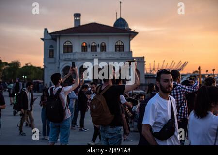 Istanbul, Turchia. 13th maggio 2022. La gente scatta foto alla spiaggia di Kadikoy. Mentre il sole tramonta nelle ore serali di Istanbul, c'è stata una festa visiva nel cielo dal molo di Kadikoy. Alcuni cittadini hanno preso il bellissimo paesaggio con il tramonto con i loro telefoni cellulari. Credit: SOPA Images Limited/Alamy Live News Foto Stock