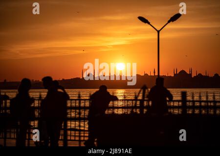 Istanbul, Turchia. 13th maggio 2022. Mentre il sole scese, la penisola storica e le sagome della gente sono state viste. Mentre il sole tramonta nelle ore serali di Istanbul, c'è stata una festa visiva nel cielo dal molo di Kadikoy. Alcuni cittadini hanno preso il bellissimo paesaggio con il tramonto con i loro telefoni cellulari. Credit: SOPA Images Limited/Alamy Live News Foto Stock