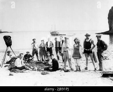 LOUISE LOVELY e direttore ALLEN HOLUBAR (in abito da bagno nero) con Movie Crew e Cast, incluso il probabile cinematografo ROY H. KLAFFKI (con tappo e tubo) E gli attori HELEN WRIGHT e SYDNEY DEANE sul set location Candid su Catalina Island California durante le riprese di SIRENE DEL MARE aka DARLINGS OF THE DÈI (in UK) 1917 regista / scenario ALLEN HOLUBAR storia Grace Helen Bailey cinematografo Roy H. Klaffki Jewel Productions / Universal Film Manufacturing Company Foto Stock