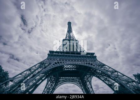 Vista ravvicinata della Torre Eiffel contro il cielo nuvoloso di colore blu Foto Stock