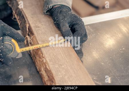 Il carpentiere misura la larghezza dell'asse con il metro del carpentiere. Foto Stock