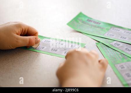 Vista ravvicinata della moneta d'argento in mano al giocatore che graffia la falsa carta della lotteria. Lotteria gioco d'azzardo concetto, gratta carte tipo di lotteria Foto Stock