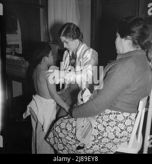 Calipatria, Valle Imperiale. Il medico di salute pubblica visitante conduce la clinica del bene-bambino nell'edificio della scuola locale adiacente al raccolto di piselli. Molte madri migratrici assistono. Foto Stock