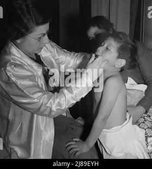 Calipatria, Valle Imperiale. Il medico di salute pubblica visitante conduce la clinica del bene-bambino nell'edificio della scuola locale adiacente al raccolto di piselli. Molte madri migratrici assistono. Foto Stock