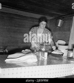 La moglie dello sharecropper del tabacco pulisce il tavolo dopo aver lavato i piatti della colazione. Contea di Person, North Carolina. Foto Stock