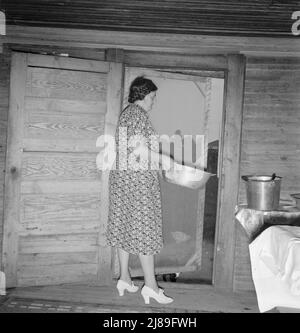 Moglie dello sharecropper del tabacco che smaltisce l'acqua della lavastoviglie dopo aver lavato i piatti della colazione. Ha messo su scarpe bianche per la fotografia. Contea di Person, North Carolina. Foto Stock