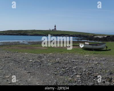 Ammira una barca a remi ormeggiata fino al faro di Bardsey Island Gwynedd Wales UK Foto Stock