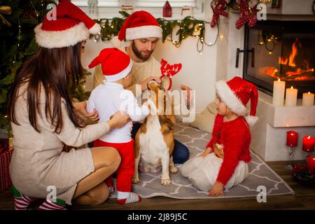 Buon Natale e Felice Anno Nuovo. Famiglia felice con cane beagle stanno aspettando il Natale a Babbo Natale cappelli Foto Stock