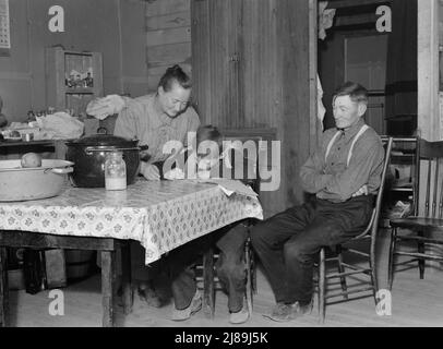 La famiglia Wardlow nella loro casa seminterrato dugout la domenica. Il ragazzo più giovane copia una ricetta per sua madre. Dead Ox Flat, contea di Malheur, Oregon. Foto Stock