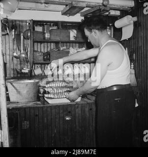 A bordo dell'Alden out di Gloucester, Massachusetts. Uomini che feriscono la barca di mare al lato della grande nave, mentre un altro pompa tutta l'acqua dal pavimento della barca. Questo finito, erano pronti per iniziare a casa con una cattura di 70.000 libbre di sgombro. Foto Stock