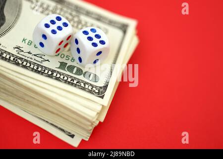 Concetto di denaro, finanza e gioco d'azzardo. Primo piano su un americano cento dollari banconote e due dadi bianchi in cima mostrando i numeri sei e sei Foto Stock