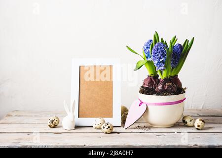 Giacinti blu, cornice fotografica e uova di quaglia su un tavolo di legno. Foto Stock