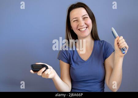 Ragazza che mostra flash glucosio monitor e penne insulina, sorridente Foto Stock