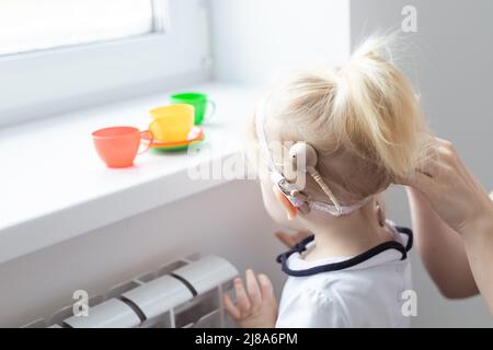 Impianto cocleare sulla testa della bambina. Concetto di apparecchio acustico e sordità Foto Stock
