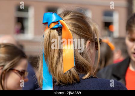 Maastricht, Limburgo meridionale, Paesi Bassi. Aprile 27, 2022. Capelli legati con un arco di colore blu e arancione, festa del Re, grande festa su un soleggiato s. Foto Stock