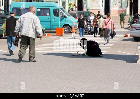 Tiraspol, Moldavia - 13 maggio 2022: Una mendicante implora vicino al parco, inginocchiandosi e pregando. Problemi sociali nei paesi dell'ex URSS, l'unreco Foto Stock