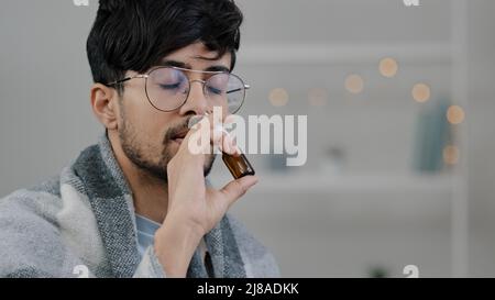 Ritratto malato arabo ispanico bearded malato uomo che soffre di allergia stagionale sintomi del virus respiratorio malessere sensazione naso che cola applica spray nasale Foto Stock