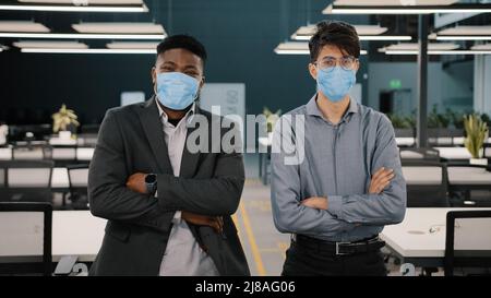 Due uomini d'affari africani Arabian colleghi business partner manager indossare maschere viso per proteggere covid 19 quarantena in sala ufficio respiratore Foto Stock