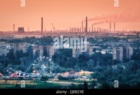 Parco divertimenti con ruota di ferro ed edifici a Mariupol Foto Stock