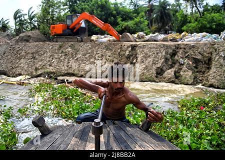 Hooghly, India. 14th maggio 2022. Un uomo ha visto cercare di avviare la sua piccola nave per essere evacuato dall'isola. Livello estremo di erosione del suolo visto sulla riva del fiume di Ganges vicino Hooghly, intorno 100km lontano dalla città Kolkata. La riva del fiume di Hooghly è altamente vulnerabile ai rischi climatici e meteorologici a causa della sua topografia e posizione geografica. Credit: SOPA Images Limited/Alamy Live News Foto Stock