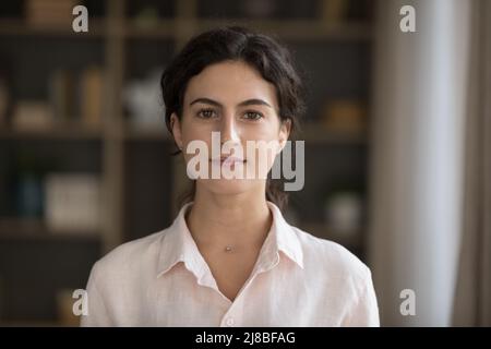 Headshot ritratto seria giovane donna che fissando la macchina fotografica posa in interno Foto Stock
