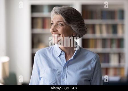 Felice più vecchio grigio capelli 60s donna in posa in ufficio domestico Foto Stock
