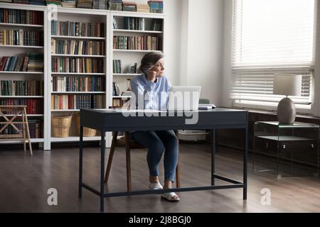 Preoccupata premurosa donna professionale di mezza età che usa il laptop Foto Stock