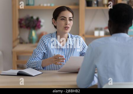 Serio datore di lavoro femminile tenuta carta riprendere, intervistando lavoro candidato maschile Foto Stock