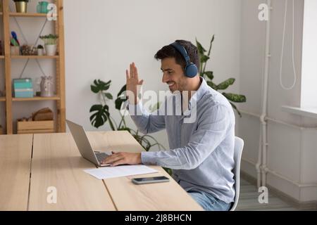 Buon professionista nelle cuffie che parla in videoconferenza Foto Stock