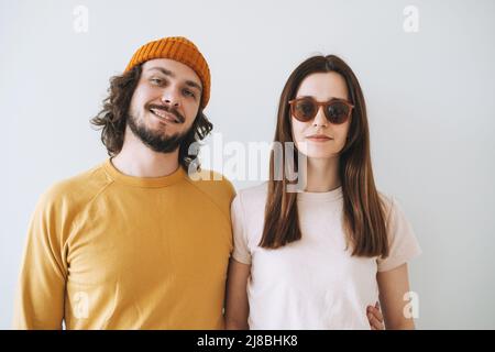 Ritratto di sorridente coppia giovane famiglia hippsters contro il muro grigio Foto Stock