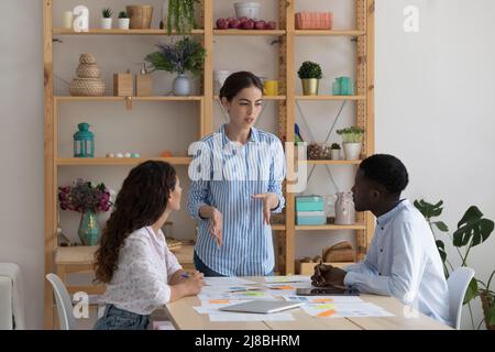 Una giovane e seria imprenditoria femminile che parla con dipendenti diversi Foto Stock