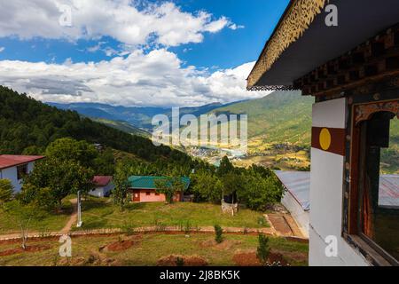 Architettura tradizionale bhutanese. Vista panoramica su una valle in Bhutan. Lungo il muro tradizionale imbiancato. Un fiume si snoda attraverso la v Foto Stock