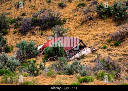Auto arrugginita abbandonata sepolta nel deserto. Foto Stock