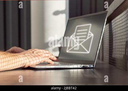 E-mail spam. Uomo che riceve posta indesiderata, messaggi indesiderati, pubblicità per truffe di denaro mentre lavora su un computer portatile. Primo piano della tastiera con le mani. Foto di alta qualità Foto Stock