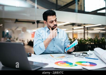 Un uomo designer islamico dal design elegante e raffinato con barba in camicia sceglie la tonalità della tavolozza dei colori Foto Stock