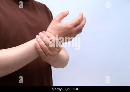 Un uomo si avvolse intorno al polso a causa del dolore al polso. Cause di artrite reumatoide, sindrome del tunnel carpale, gotta. Assistenza sanitaria e concetto medico. Foto Stock