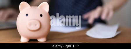 Piggy banca per risparmiare denaro sul tavolo del professionista finanziario Foto Stock