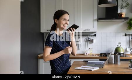 Ragazza studentesca felice usando assistente vocale virtuale per la ricerca del Internet Foto Stock