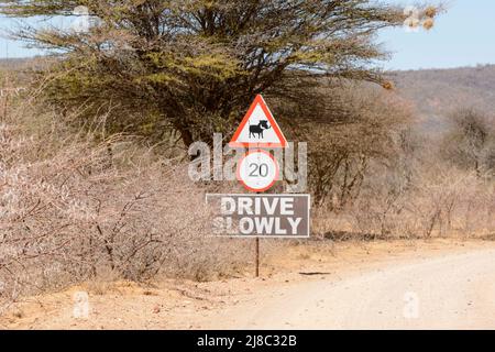 Un cartello stradale avverte i conducenti di prestare attenzione alle guerre e di guidare lentamente, Namibia, Africa sudoccidentale Foto Stock