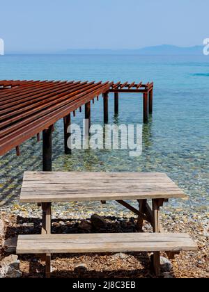 Tavolo e panca in legno sulla riva del mare. Tavolo da picnic fatto a mano vicino al mare. Concetto di luogo di viaggio di riposo Foto Stock