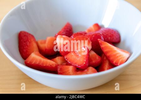 Molte fragole tagliate in ciotola sono pronte da mangiare con cucchiaio d'argento o come delizioso dito e snack sano con frutta rossa e vitamine su legno Foto Stock