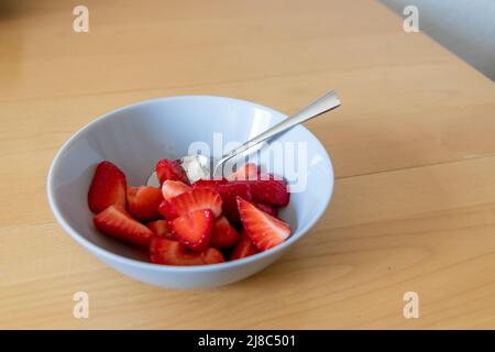 Molte fragole tagliate in ciotola sono pronte da mangiare con cucchiaio d'argento o come delizioso dito e snack sano con frutta rossa e vitamine su legno Foto Stock