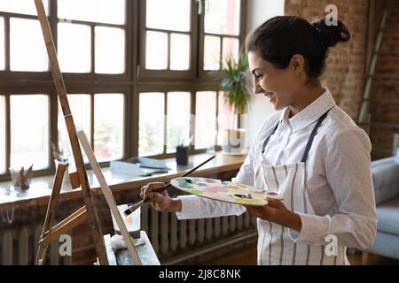 La donna pittore indiana pratica la pittura su tela con vernici Foto Stock