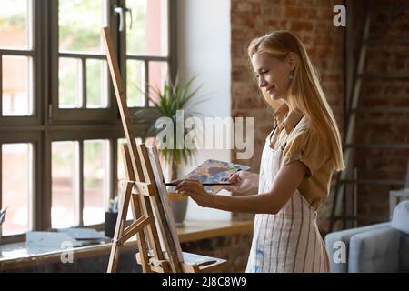 Pittore donna pittura immagine su tela sorrisi godere di hobby creativo Foto Stock