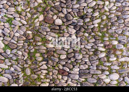 Antique path way made of smooth round stone  from the sea. Foto Stock