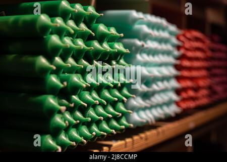 Candele colorate a bastoncino disposte su scaffali e ordinate per colore in un negozio di candele. Foto Stock